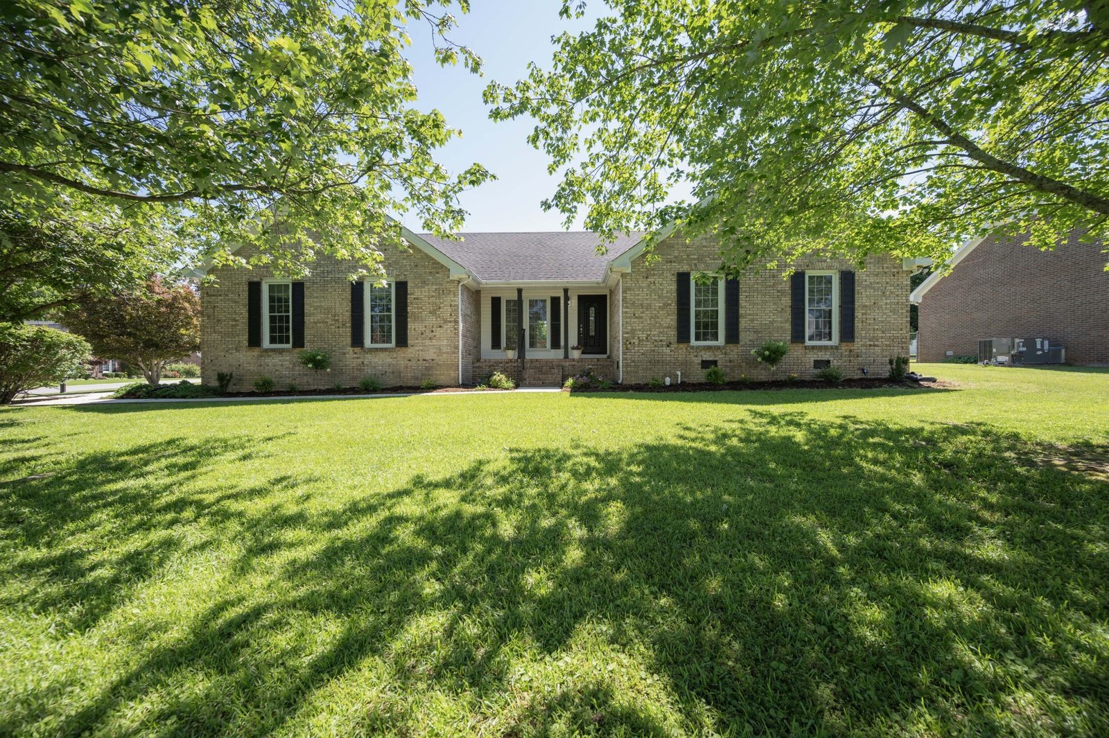 Front of the brick ranch home with shade trees at 152 Greenbriar Circle