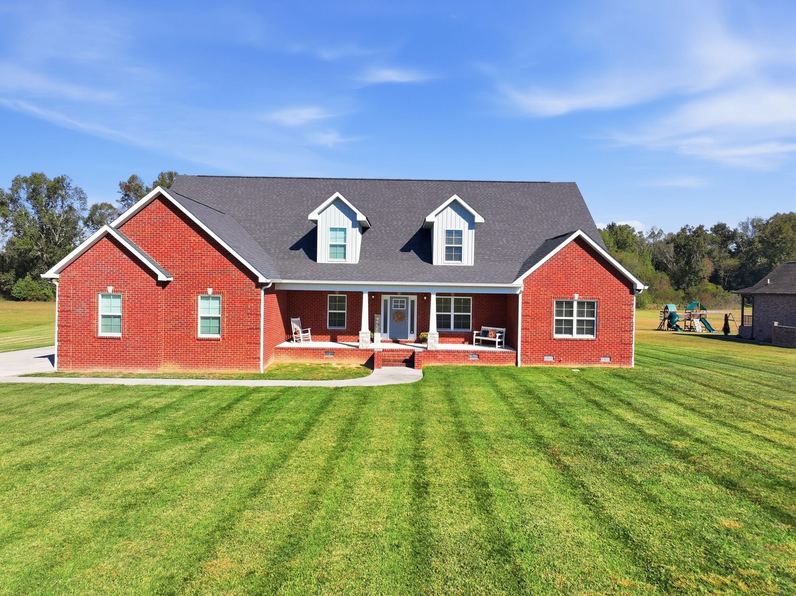 Front of the red brick home with dormers and a covered front porch at 241 Roberts Creek Circle